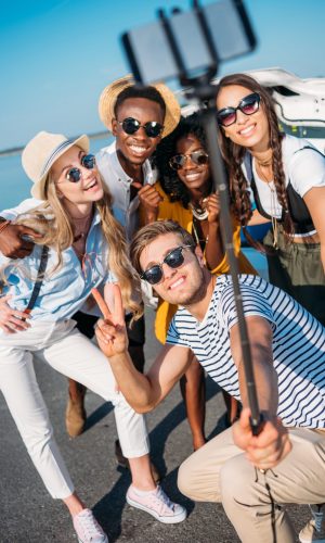 selective focus of multiethnic happy friends taking selfie together on smartphone